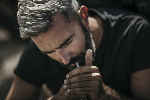 Mature man with beard igniting cigarette - MJRF00796