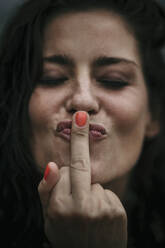 Woman with eyes closed kissing middle finger - MJRF00811