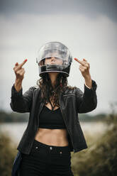 Woman wearing helmet showing middle fingers - MJRF00817