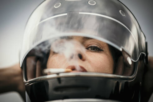 Woman wearing helmet smoking cigarette - MJRF00820