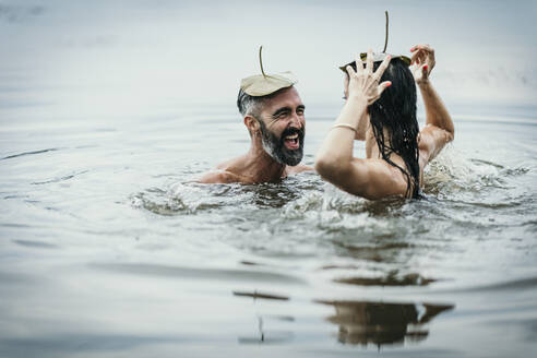 Glücklicher reifer Mann mit Frau, die zusammen im See Spaß haben - MJRF00825