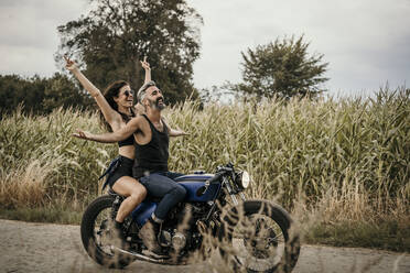 Unbeschwerter Mann mit Frau auf dem Motorrad - MJRF00833