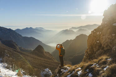 Wanderer, der auf einem Berg stehend mit seinem Smartphone fotografiert - MCVF01022