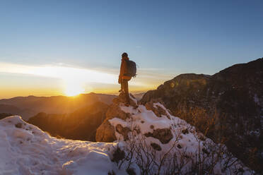 Hiker standing on rock at sunset - MCVF01032
