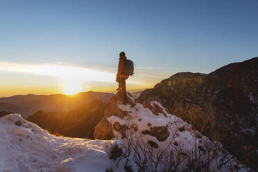 Wanderer steht bei Sonnenuntergang auf einem Felsen - MCVF01032