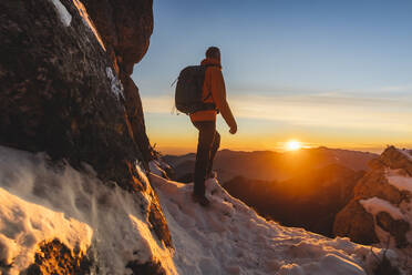 Mature hiker standing in front of mountains at sunset - MCVF01034