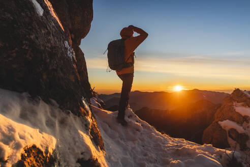 Wanderer genießt den Sonnenuntergang auf einem Berg stehend - MCVF01035