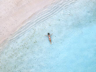 Frau entspannt und schwimmt im Meer am Strand - KNTF06853