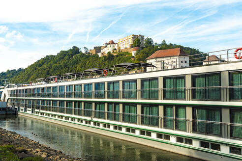 Deutschland, Bayern, Passau, Luxusfähre angedockt an der Donau mit der Veste Oberhaus im Hintergrund - TAMF03745