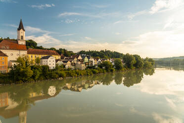 Germany, Bavaria, Passau, Houses reflecting in Inn river at sunset - TAMF03761