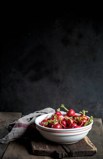 Fresh red radishes in bowl at table - SBDF04591