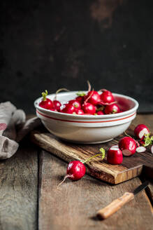 Fresh radishes in bowl with knife on table - SBDF04593