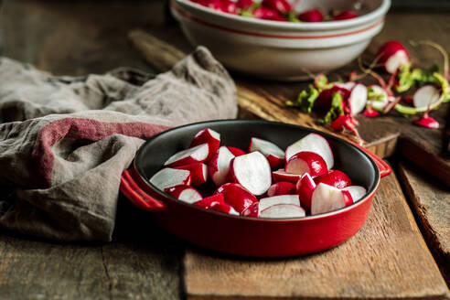 Red radishes in casserole dish at table - SBDF04595