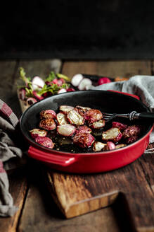 Freshly baked radishes in casserole dish at table - SBDF04597