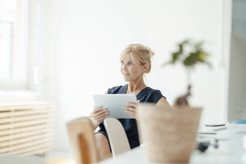 Nachdenkliche Geschäftsfrau mit Tablet-PC im Büro - JOSEF15288