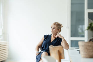 Thoughtful mature businesswoman with tablet computer at workplace - JOSEF15290