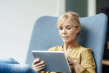Mature businesswoman using tablet PC on armchair - JOSEF15307