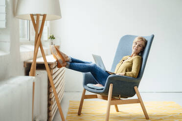 Businesswoman with legs crossed at ankle resting on armchair - JOSEF15310