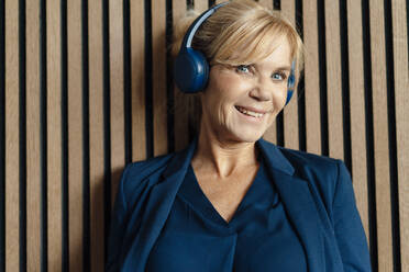 Glückliche Geschäftsfrau, die Musik über kabellose Kopfhörer hört - JOSEF15336