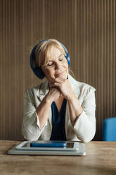 Geschäftsfrau hört Musik mit drahtlosen Technologien auf dem Schreibtisch - JOSEF15357