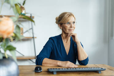 Thoughtful businesswoman wearing eyeglasses at desk in office - JOSEF15387