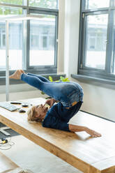 Glückliche Geschäftsfrau macht Halasana Yoga-Pose und sprechen auf Handy im Büro - JOSEF15394