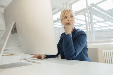 Thoughtful mature businesswoman at desk in office - JOSEF15423