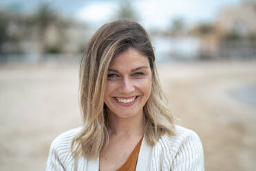 Smiling beautiful young blond woman at beach enjoying weekend - JOSEF15450