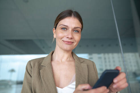 Lächelnde junge Geschäftsfrau mit Mobiltelefon - JOSEF15504