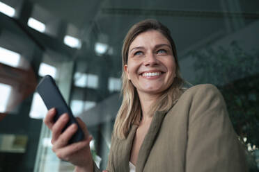 Cheerful blond businesswoman with smart phone - JOSEF15512