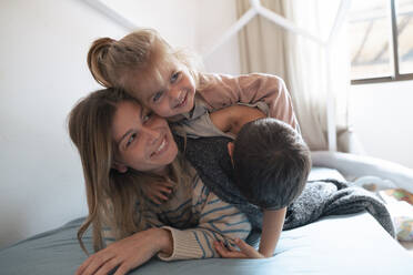 Kinder liegen auf der Mutter und genießen im Schlafzimmer zu Hause - JOSEF15516