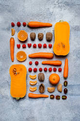 Stilleben aus verschiedenen, aufeinander abgestimmten Herbstgemüsen, aufgeschnittenen Kürbissen, Tomaten, Karotten, Mandarinen, Himbeeren und Haselnüssen von oben - ADSF41952