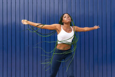 Strong young woman doing exercises with resistance band over colored  background. Fitness female working out with