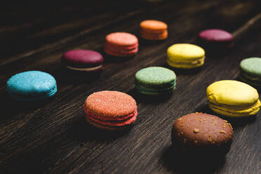 Colorful French macaroons with various fillings placed on wooden table in dark background - ADSF42014