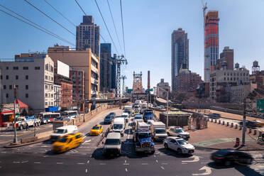 Modern vehicles driving on asphalt road under Roosevelt Island Tramway against cloudless blue sky on sunny day in New York, USA - ADSF42061