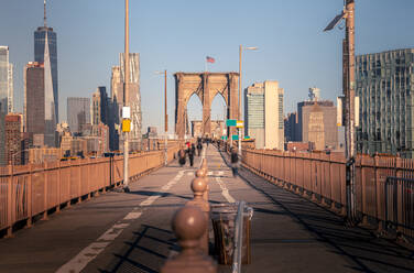 Spaziergänger auf der Brooklyn Bridge vor wolkenlosem blauem Himmel in Manhattan, New York, USA - ADSF42073