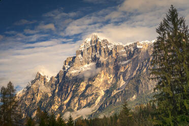 Majestätisches Tal der Dolomiten mit hohen Bergen und Laubbäumen im Herbst mit schweren Wolken darüber, Italien - ADSF42142