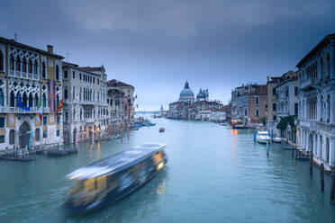 Langzeitbelichtung des ruhigen Wassers mit verschwommenen Gondeln im Canal Grande von Venedig mit Blick auf die Basilika Santa Maria della Salute unter ruhigem Himmel am Abend, Venedig, Italien - ADSF42154