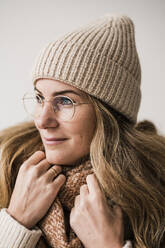 Thoughtful woman wearing warm clothing and eyeglasses against white background - JOSEF15521