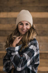 Beautiful smiling woman wearing knit hat standing in front of wall - JOSEF15533