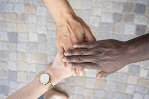 Multirassische Freunde stapeln ihre Hände auf dem Fußweg - TAMF03791