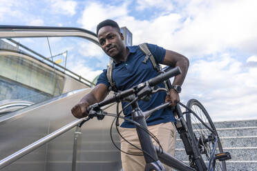 Man carrying bicycle on staircase - TAMF03796