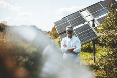 Reifer Mann mit VR-Brille vor Sonnenkollektoren stehend - JOSEF15557