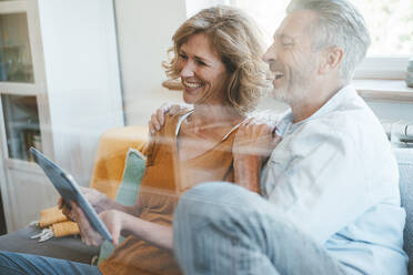 Happy mature man and woman using tablet PC seen through glass - JOSEF15656