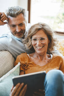 Glückliche Frau mit Brille benutzt Tablet-PC mit Mann zu Hause - JOSEF15662