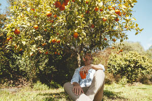 Nachdenklicher Mann mit Kaffeetasse unter einem Baum sitzend - JOSEF15705