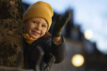 Smiling boy wearing yellow knit hat in winter at night - NJAF00076