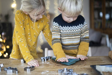 Junge, der von seiner Schwester zu Hause eine Form auf den Teig formt - NJAF00086