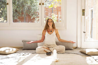 Happy shamanic woman with rin gong and healing crystal in living room - MEGF00344