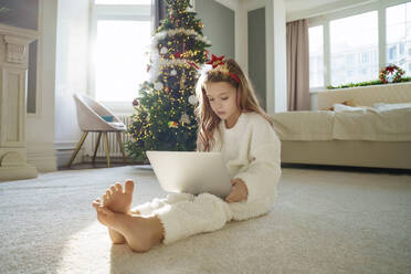 Mädchen mit Laptop auf dem Teppich im Schlafzimmer zu Hause - MDOF00379